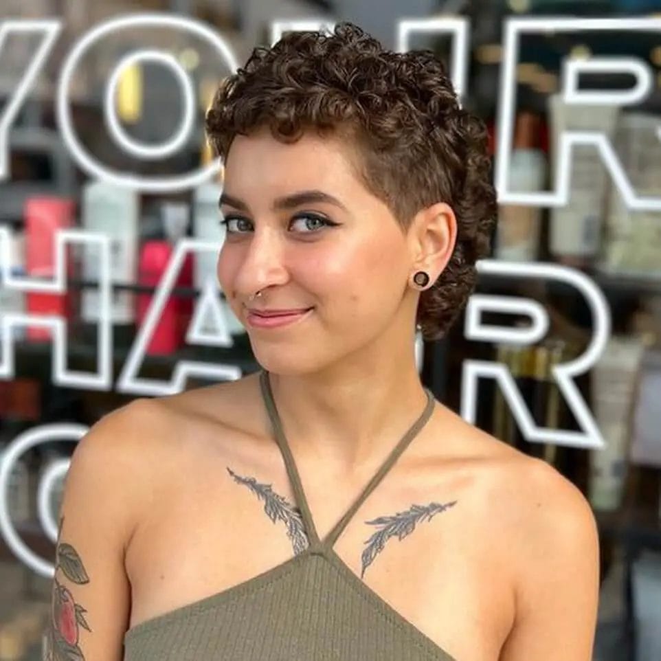 Short haircut with a bold undercut and dense, tight curls.