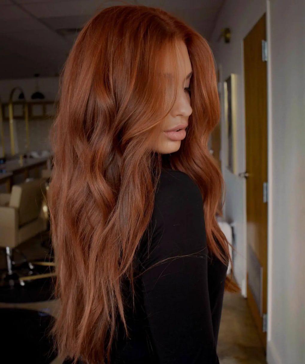 Muted copper hair in a relaxed, side-parted style with gentle waves.