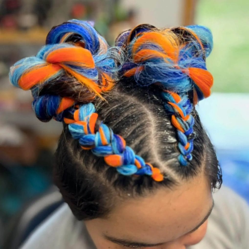 Neon orange and blue yarn braids twisted into a sculptural high bun