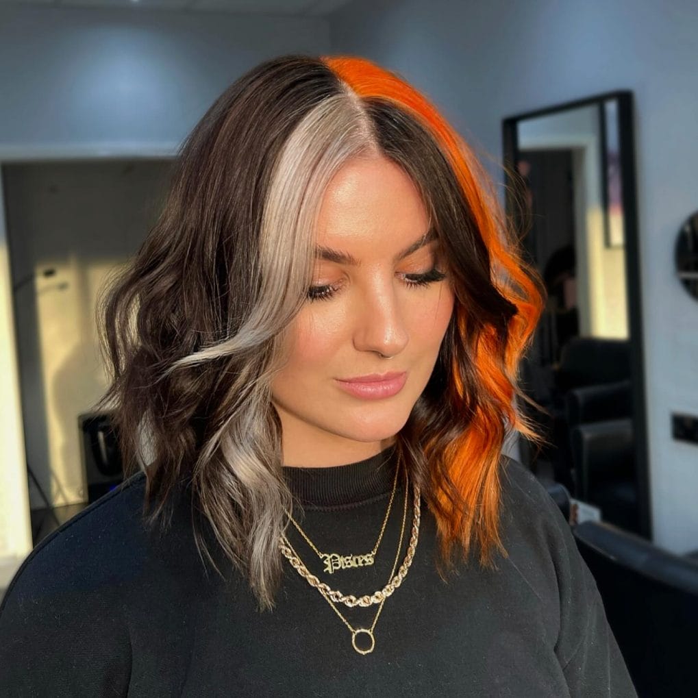 Chic lob with bold orange streak against silver and dark roots