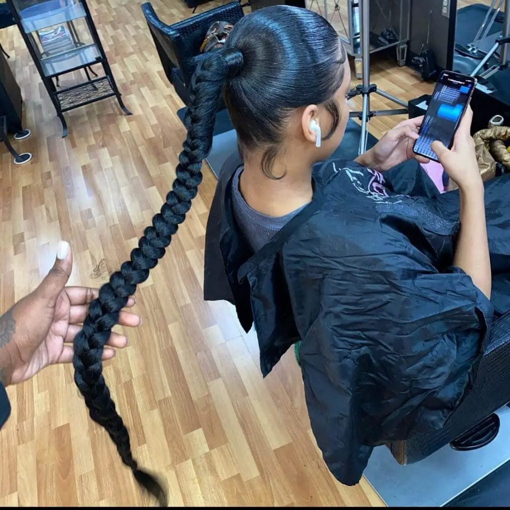 Glossy, oversized black braid starting at the crown, forming a thick ponytail.