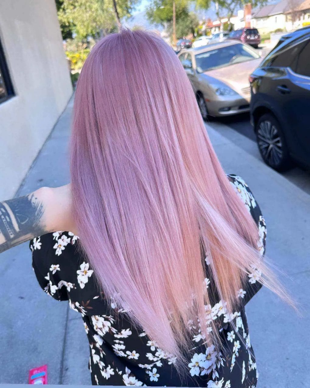 Long straight hair with playful pastel pink balayage from darker roots.