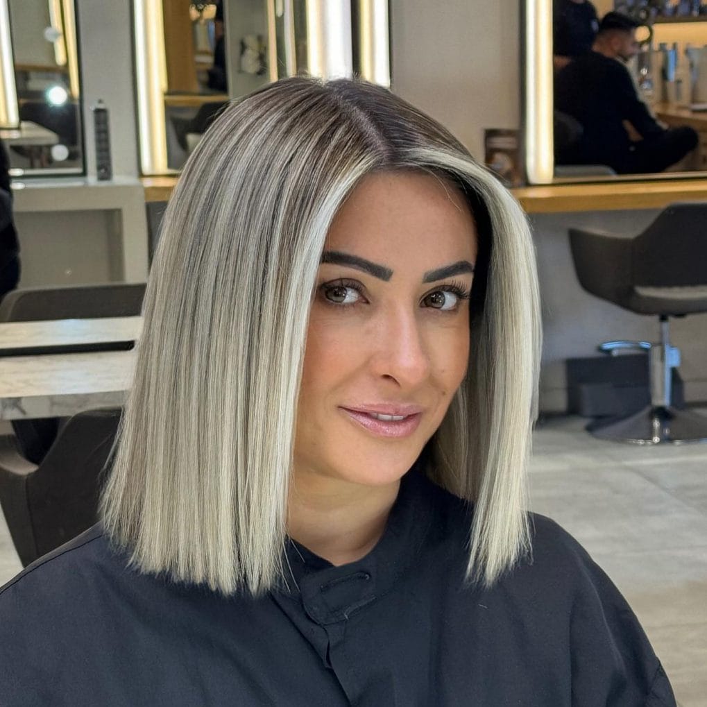 Sleek platinum blonde blunt bob at collarbone with dark roots