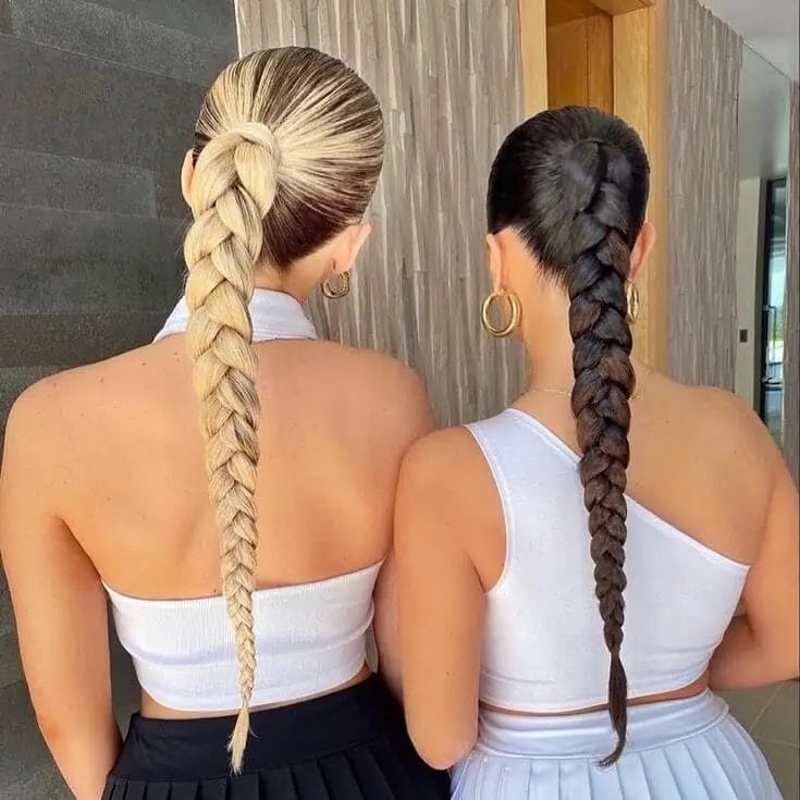 Platinum fishtail and glossy black traditional braid, both as ponytails.