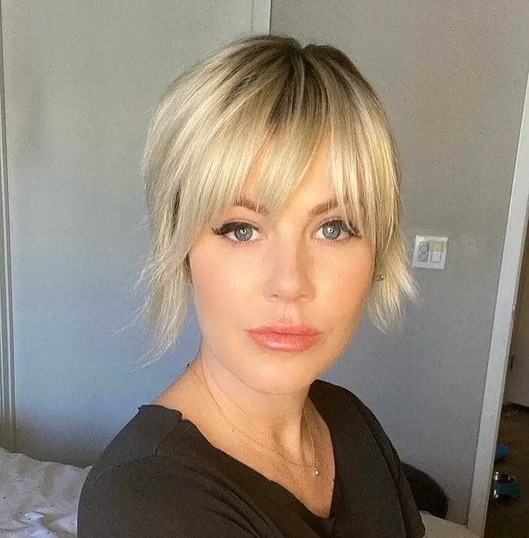 Modern short Bardot bangs with feathery layers in a striking platinum blonde hue, balancing edgy and chic.