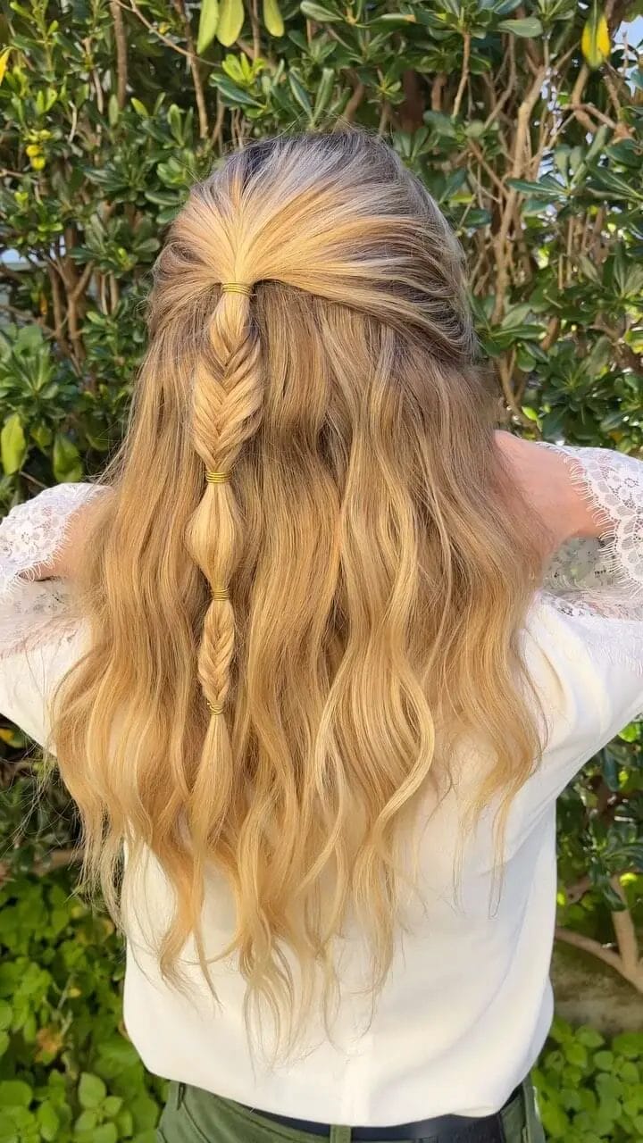 Playful centered half-up braid with golden waves tied at intervals