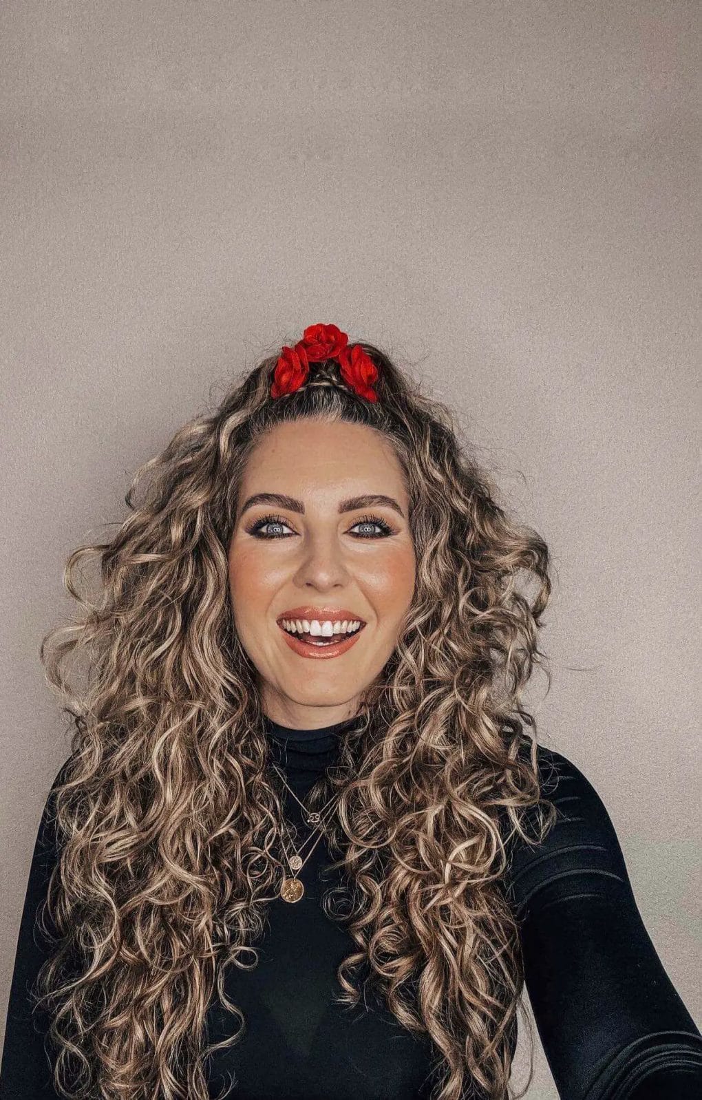 Vibrant red floral headband on top of voluminous curls for a playful birthday look.