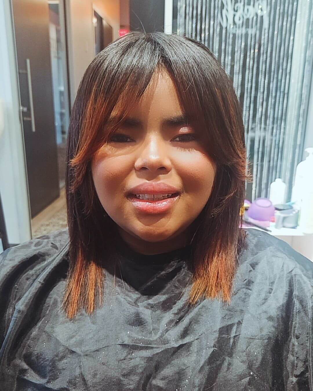 Polished medium-length cut with reddish highlights and curtain bangs