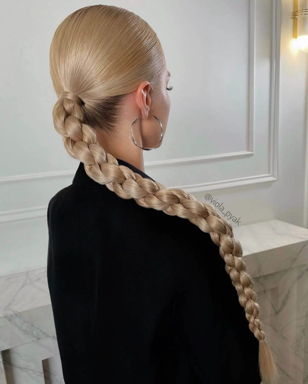 Sleek, polished sandy blonde braid forming a smooth ponytail.