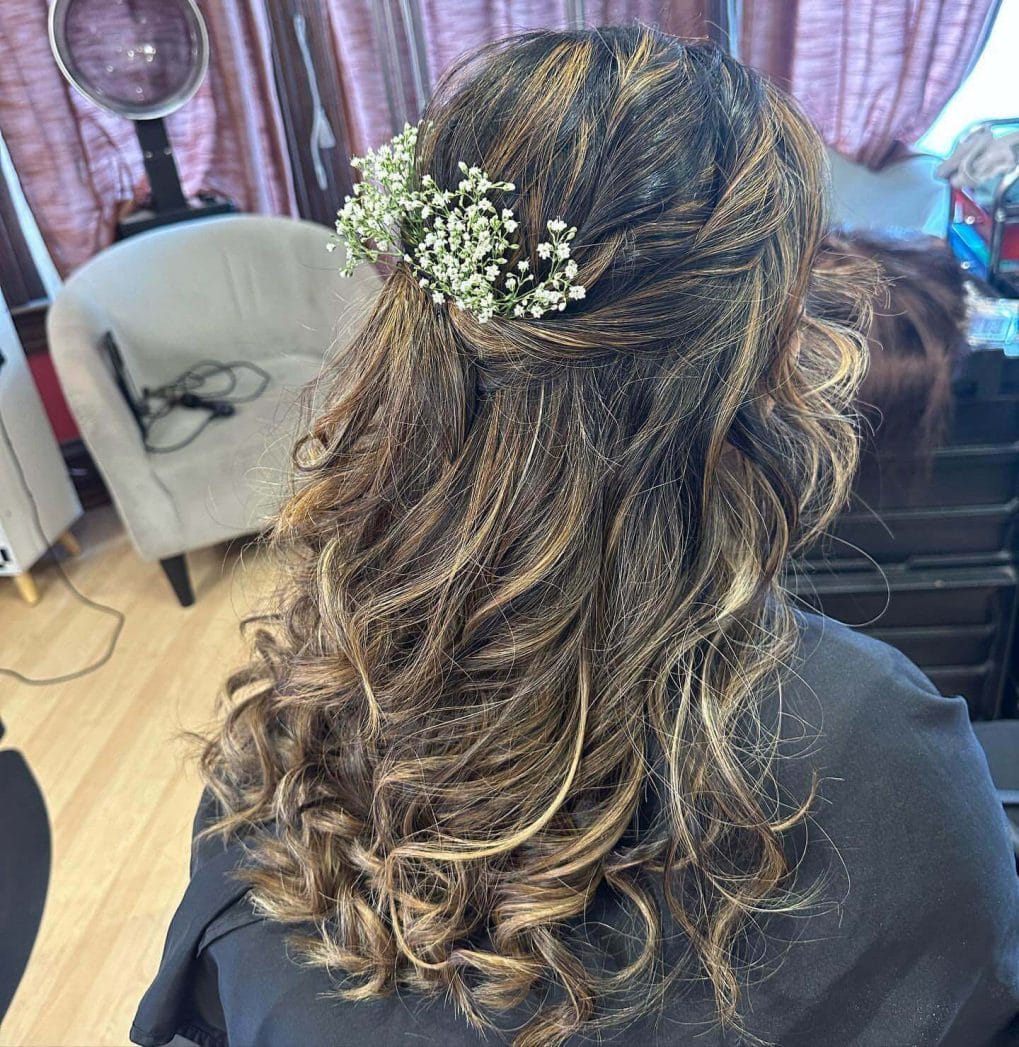 Half-up hairstyle with cascading curls and blonde highlights