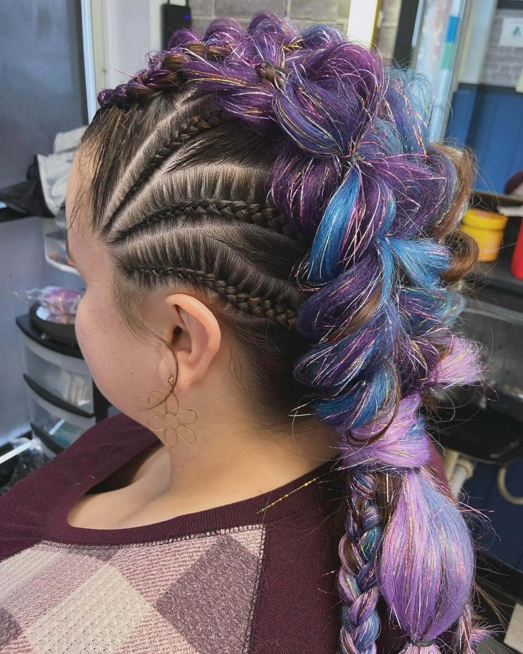 Cornrows that lead to a ponytail of twisted purple and blue braids