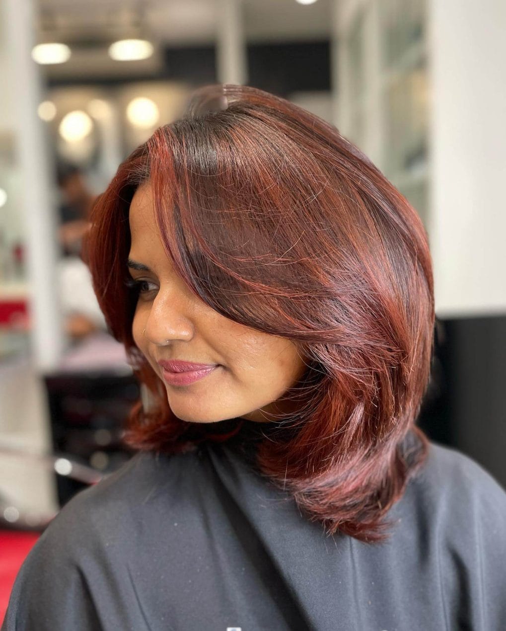 Auburn shoulder-length hair with side-swept fringe and soft waves.