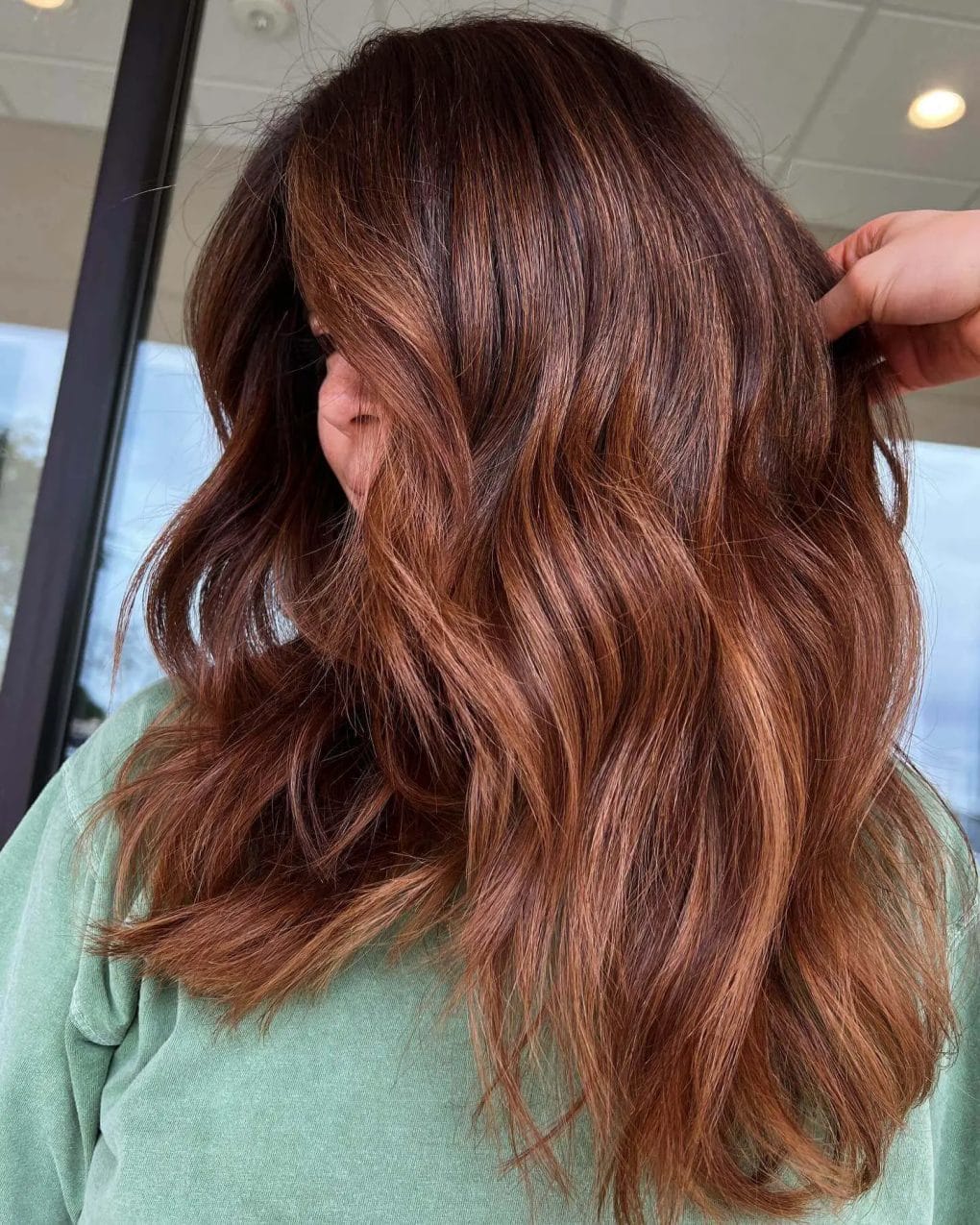 Radiant copper hair with shadow root, voluminous waves, and tousled finish.