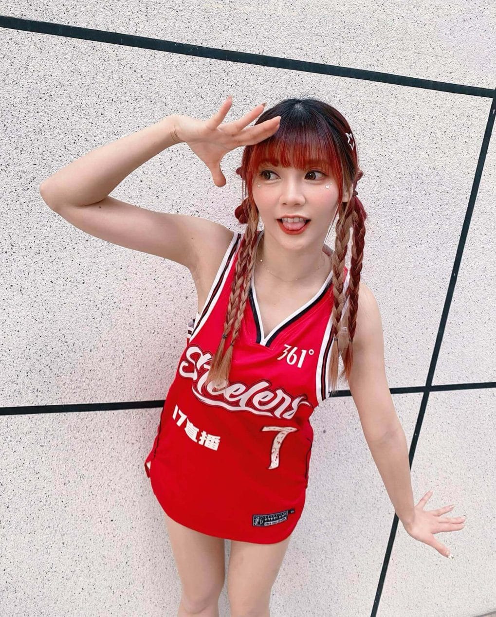 Red-haired cheerleader with playful braids and straight bangs