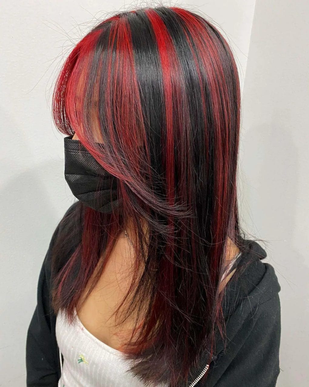Shoulder-length with red chunky highlights on black, textured layers framing face.