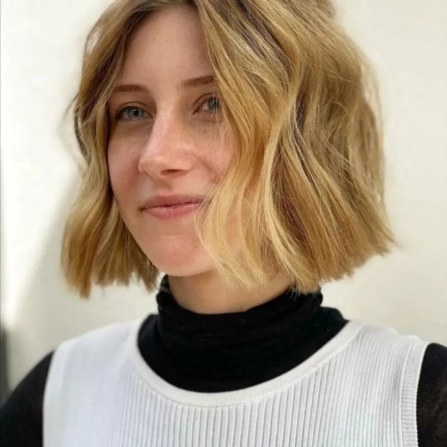 Relaxed '90s bob with textured waves, honey-blonde highlights, and a side part