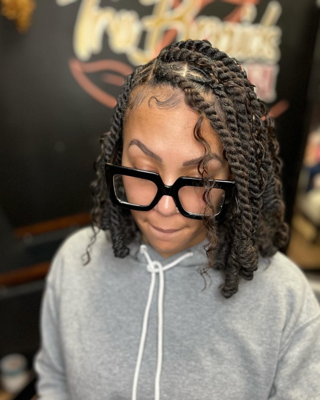 Deep side-parted rich brown kinky twists with neat baby hairs and glasses