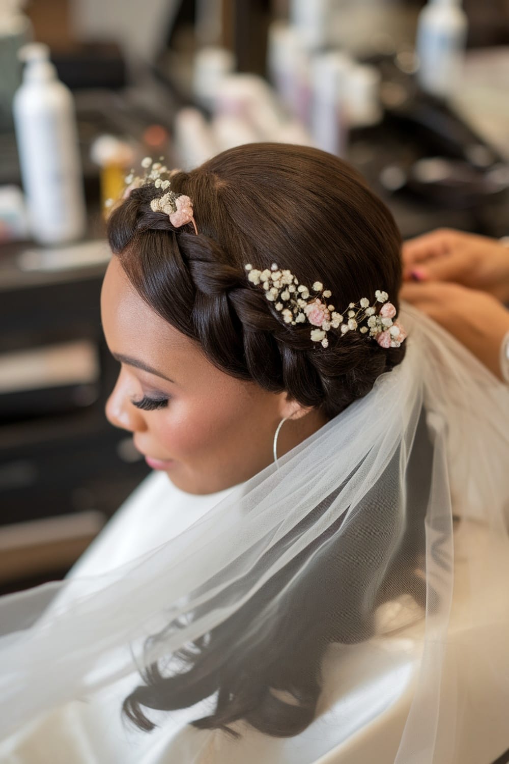 A bride with a romantic braided crown hairstyle, adorned with floral accents and a veil.