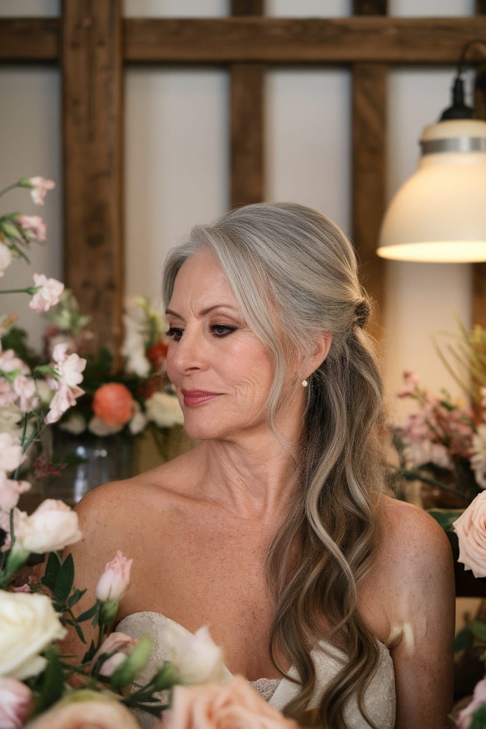 A woman with long, flowing hair styled in a romantic half-up hairstyle, surrounded by flowers.