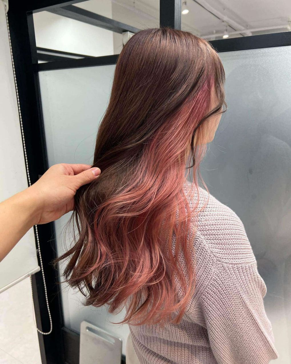 Soft rose gold to peach waves in playful mid-length cut