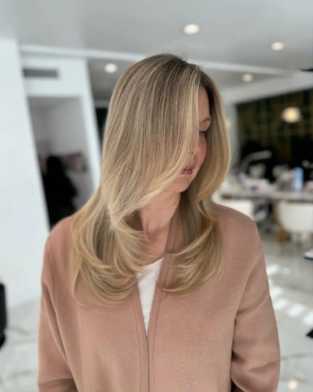 Long sandy blonde hair with subtle curls at the ends and layered styling
