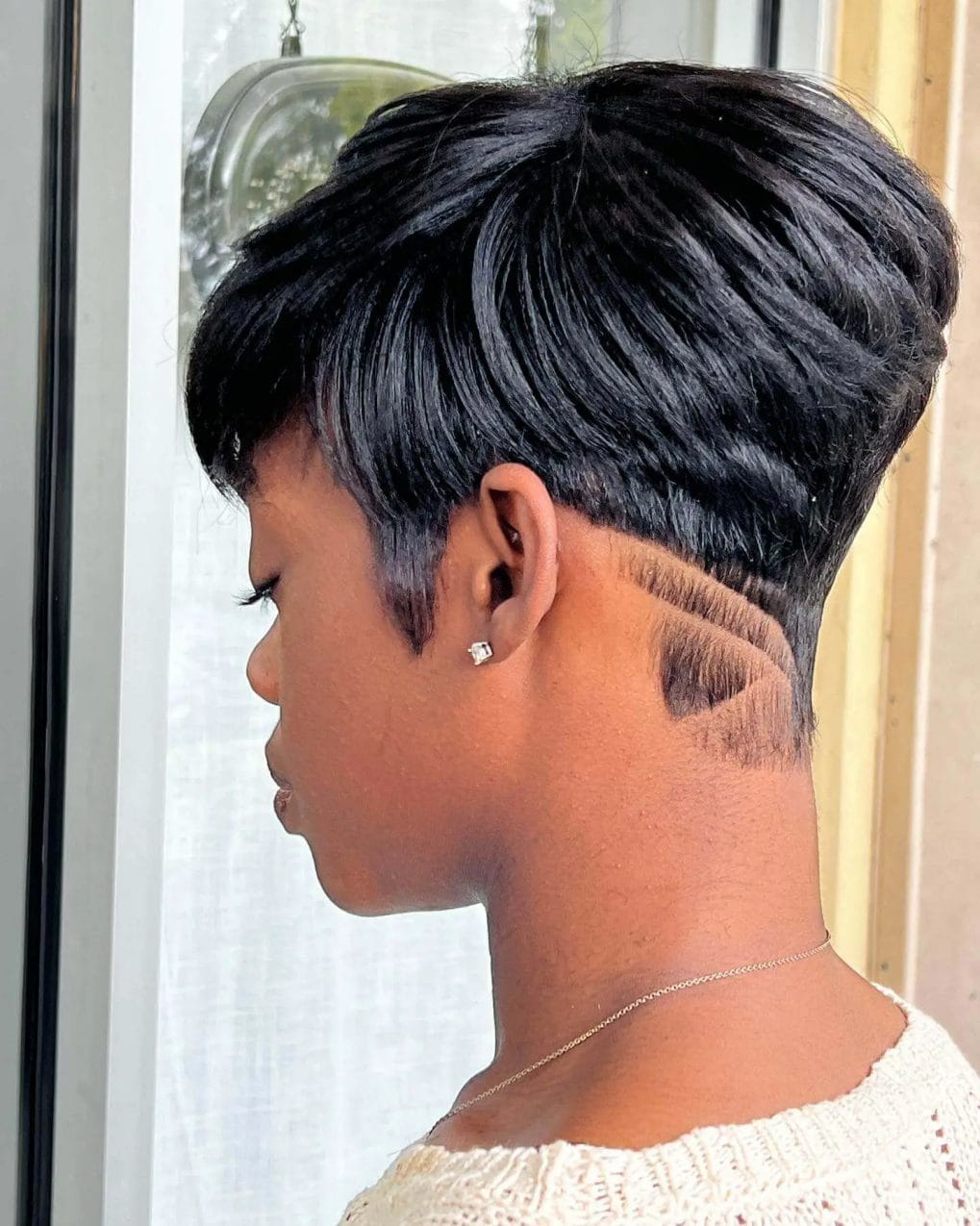 Sleek pixie cut with sculpted waves flowing into an etched wave undercut design.
