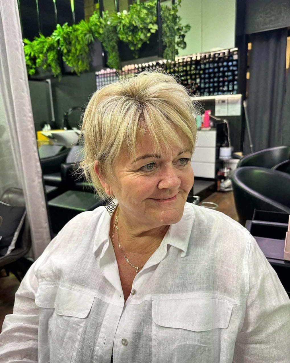 Short layered haircut with volume, light blonde color, and straight, see-through bangs.