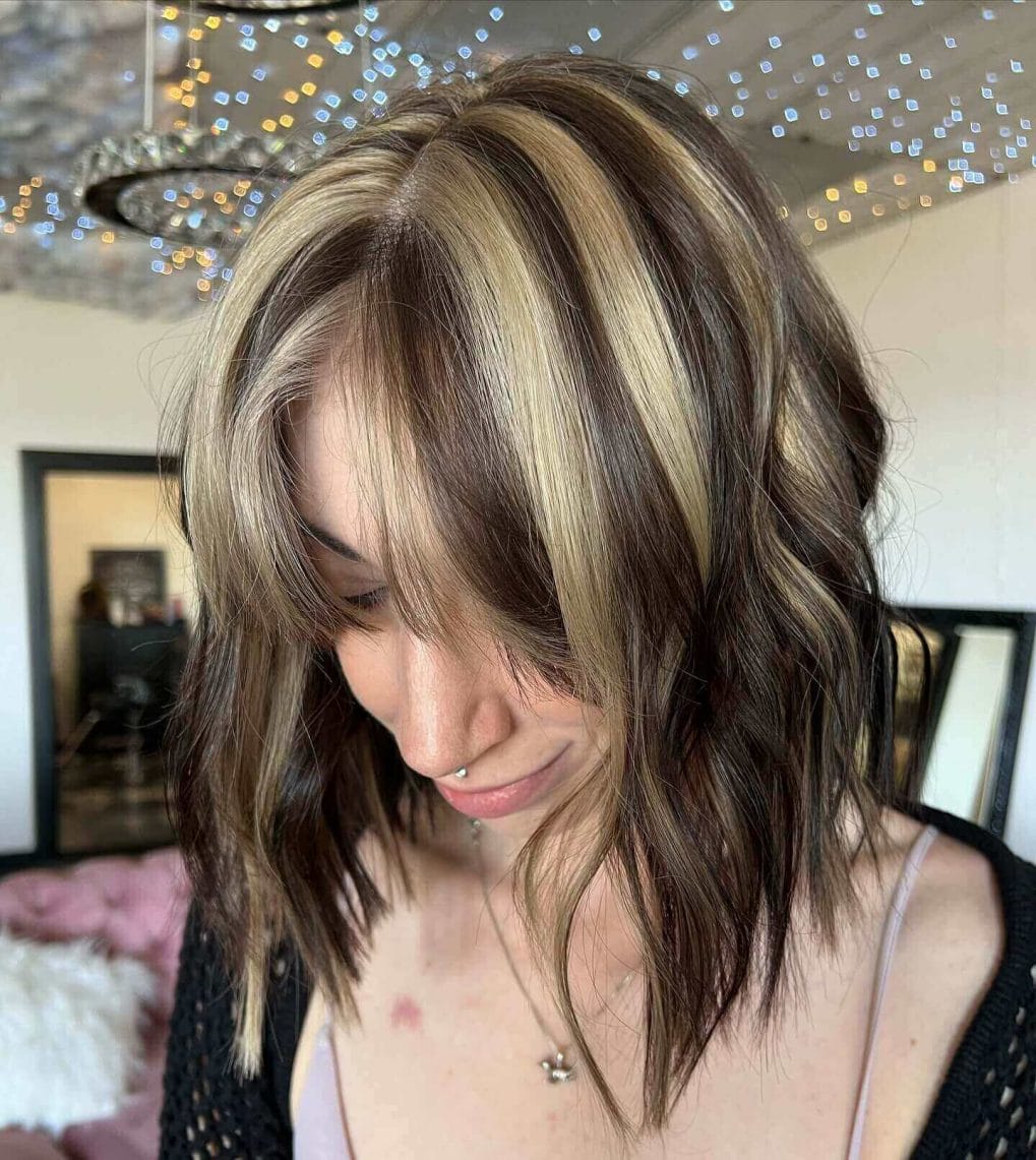Short wavy hair with blonde and dark brown chunky highlights and curtain bangs