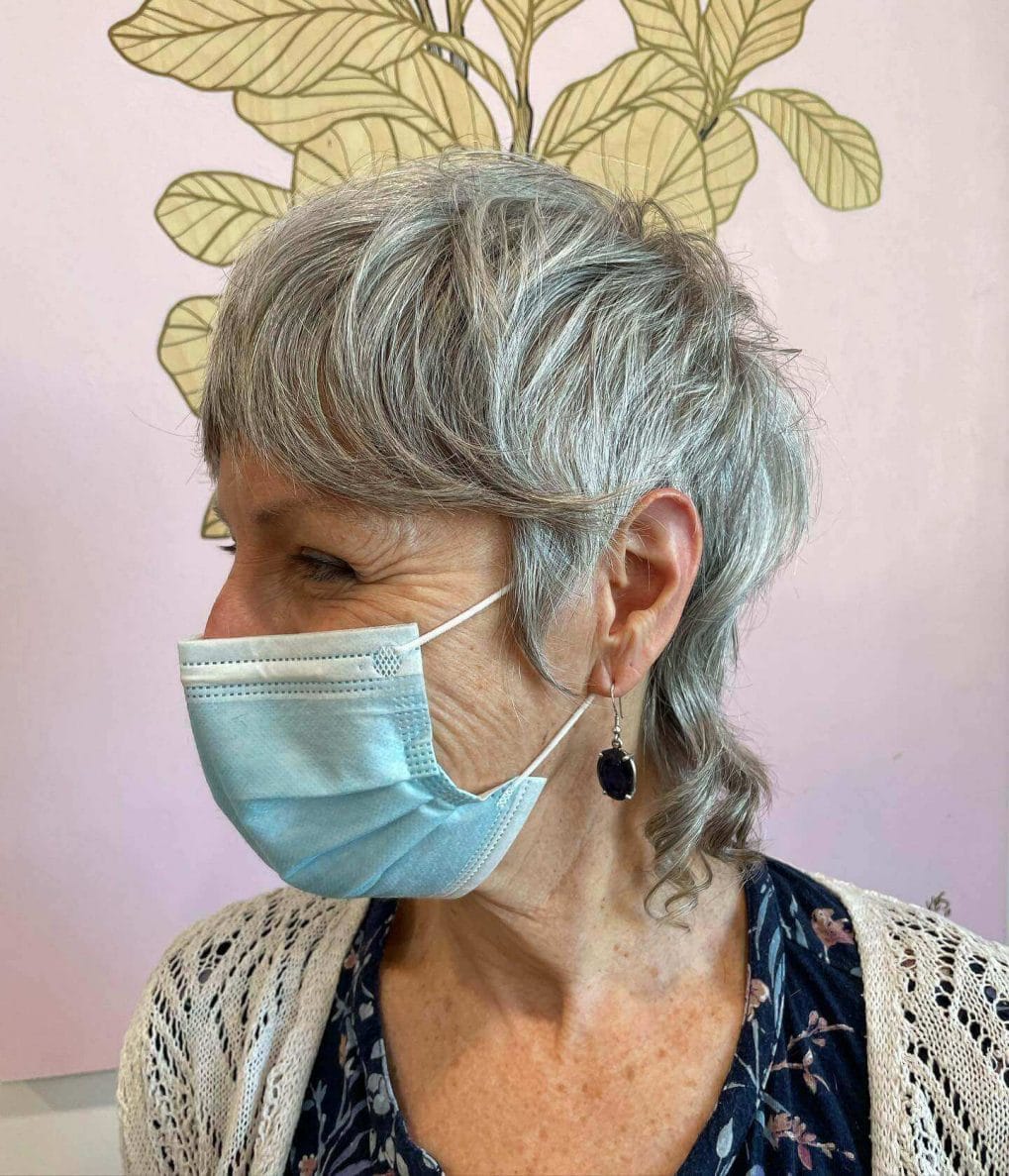 Sophisticated pixie cut with natural silver highlights and soft, layered bangs.