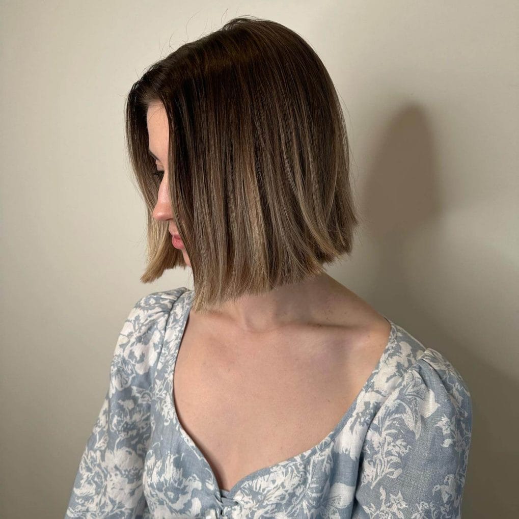 Sleek brunette blunt bob with light blonde balayage and sharp edges.