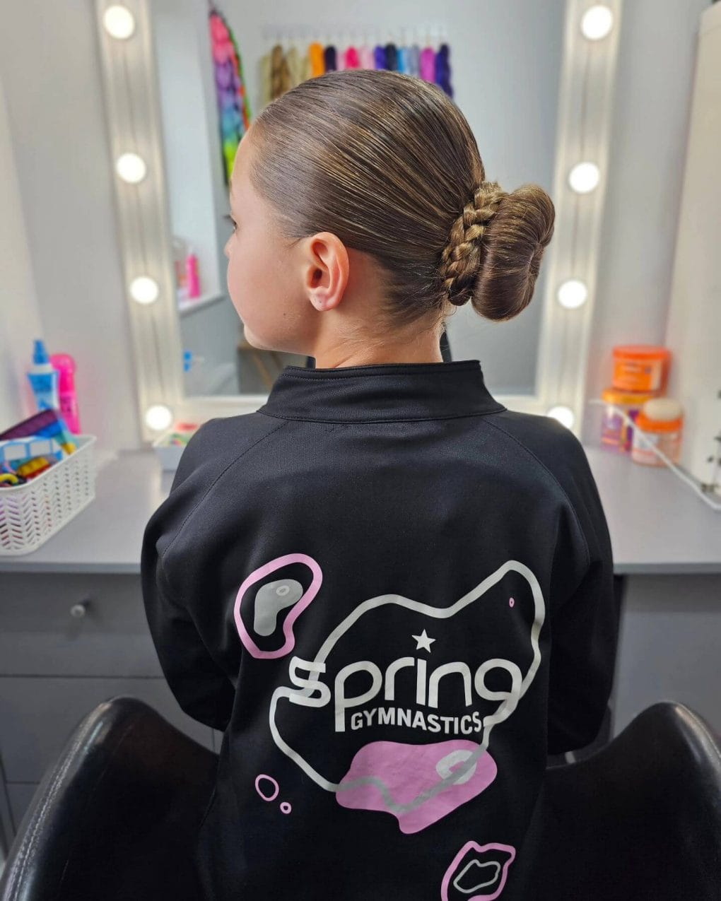 Polished competition bun secured at the back for gymnastic performance, reflecting tidiness and focus