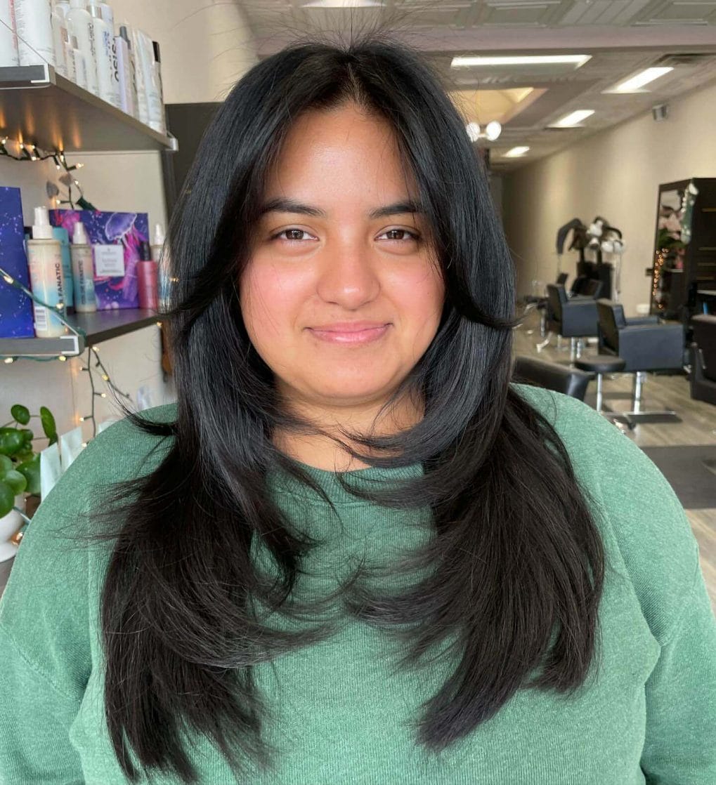 Sleek dark layers with modern 90s curtain bangs