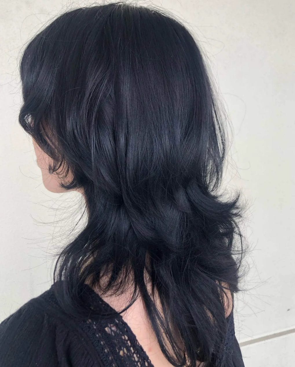 Sleek inky black octopus haircut with graduated layers for mysterious allure.