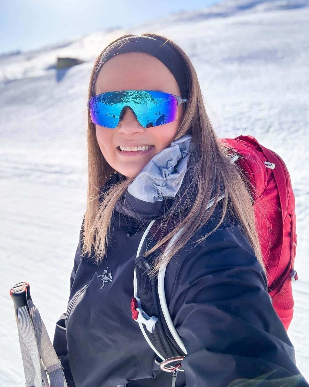 Woman with sleek headband holding back straight hair on snowy slope