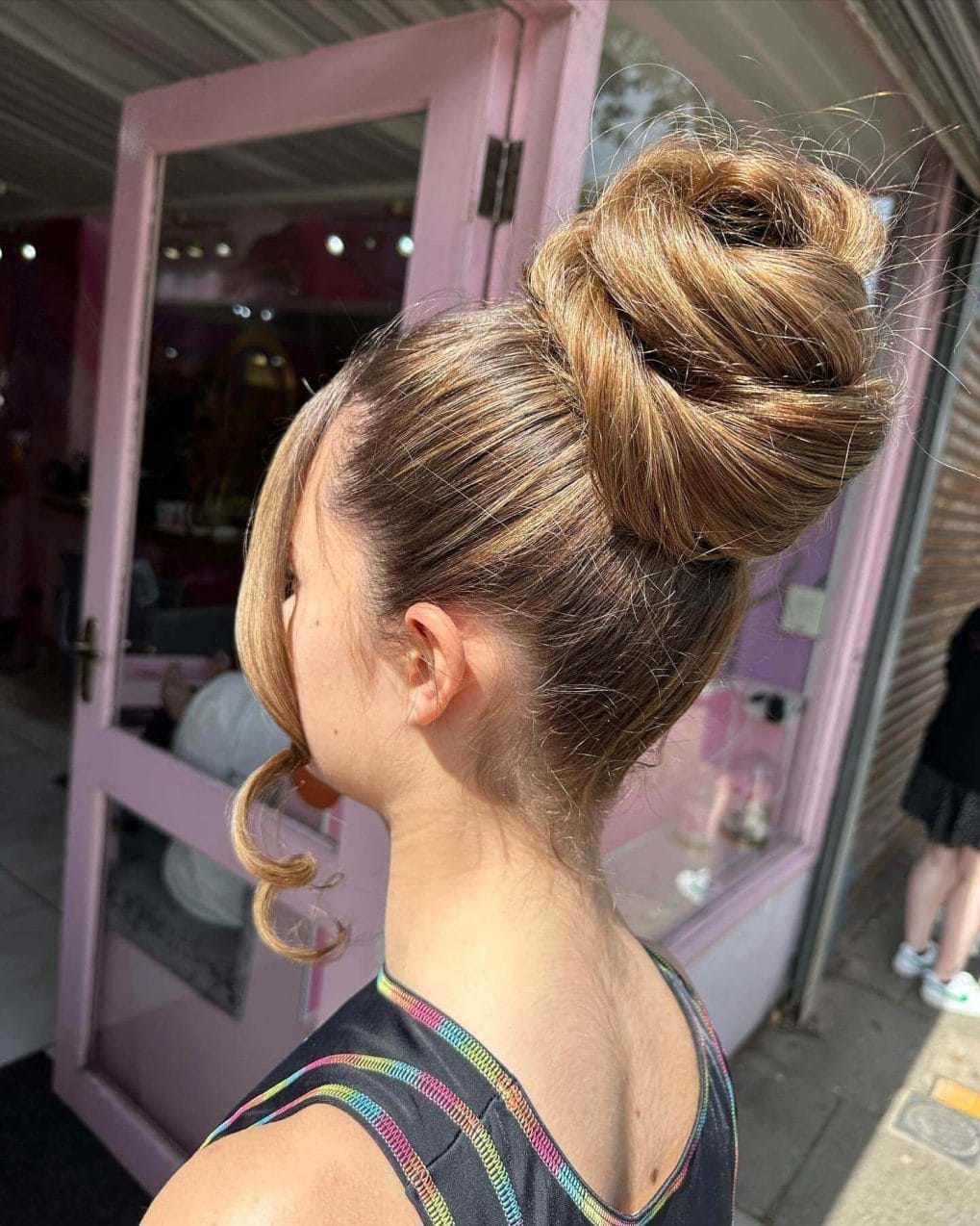 Sleek high bun with a curled tendril framing the face