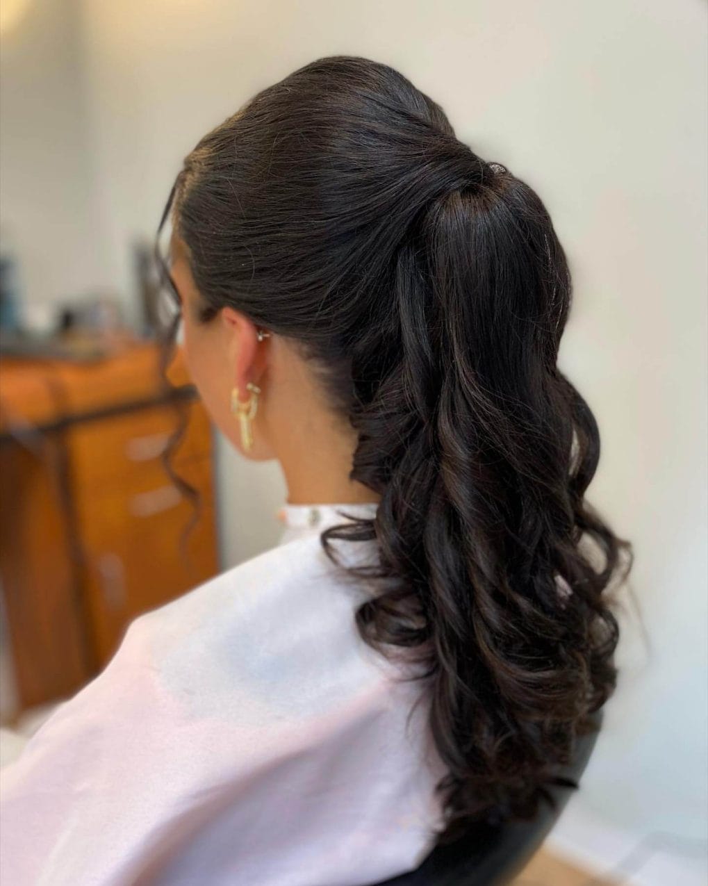 Sleek high ponytail with voluminous curls and polished top