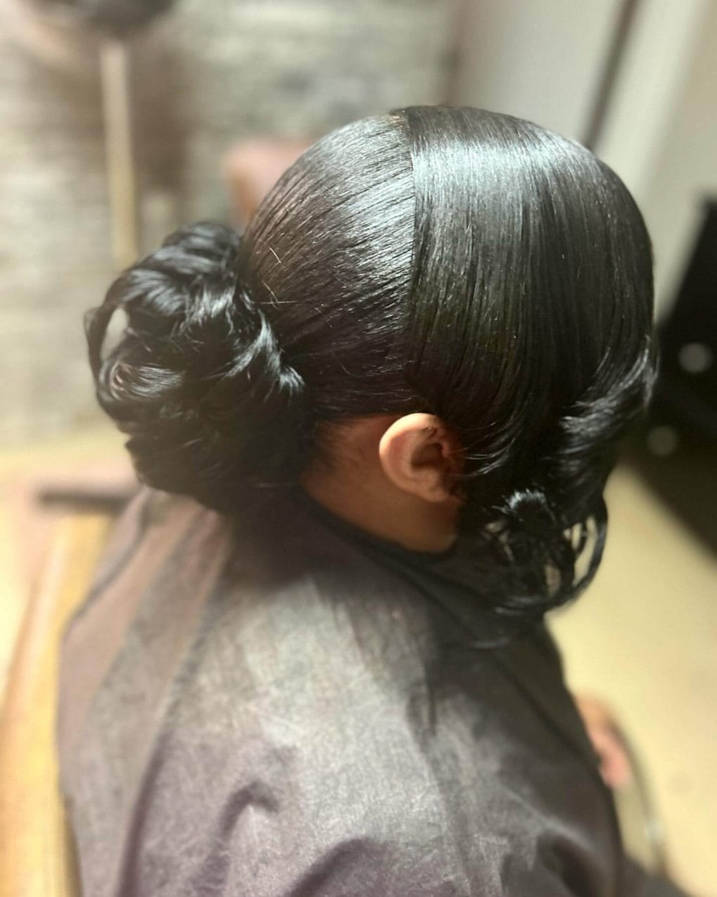 Sleek low bun with smooth dark hair and middle part