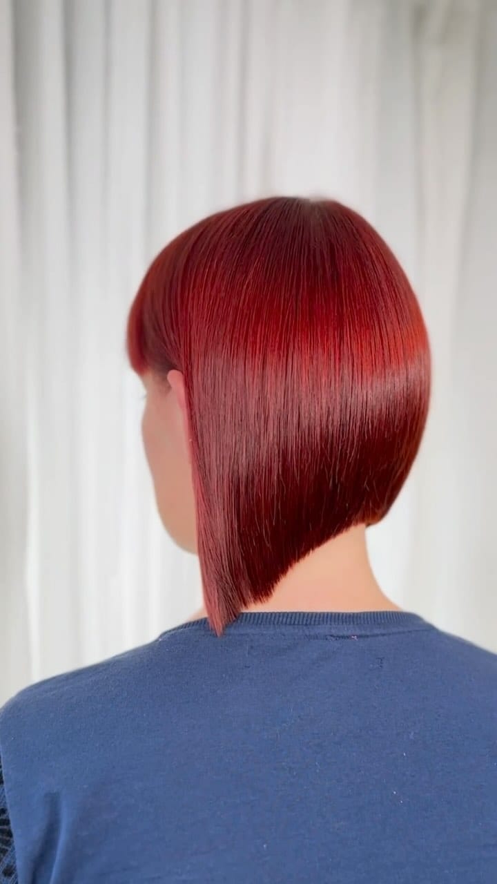 Sleek red bob below the ear with a precise cut