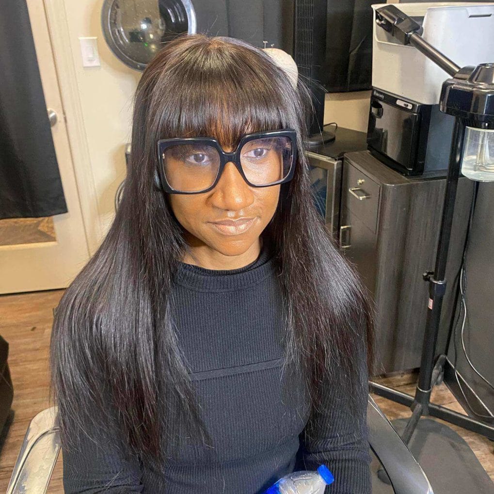 Sleek ebony long hair with full straight bangs and square glasses frames.