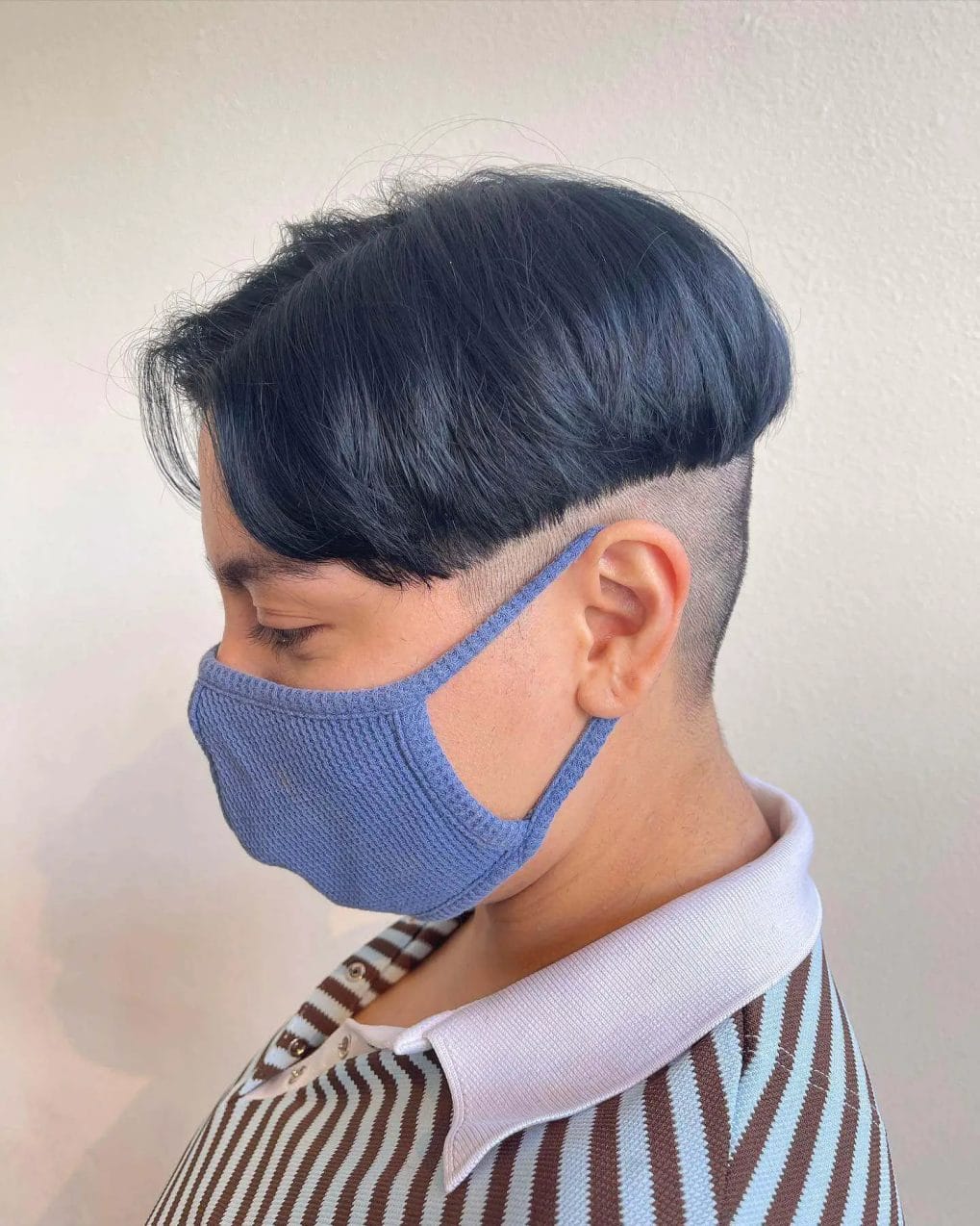 Contemporary slicked-back hairstyle with a deep blue undercut and close-shaved sides.
