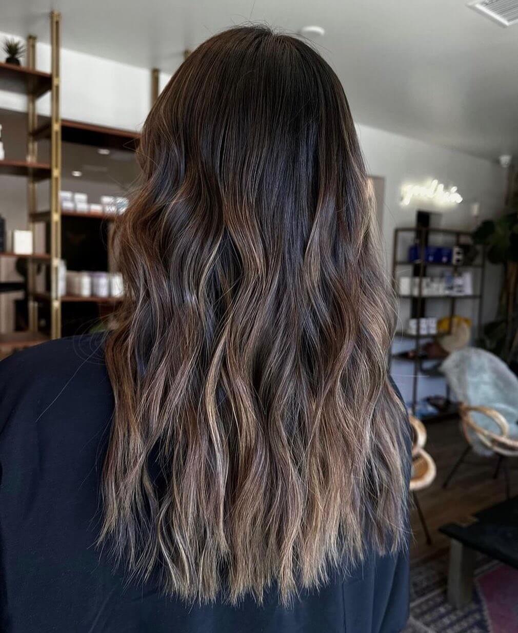 Smoky ash balayage on long layered espresso hair.