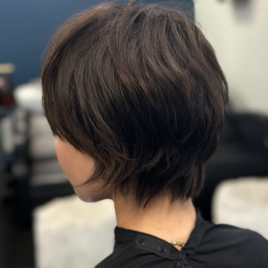 Sleek layered pixie bob in rich dark brown styled with a slight flip at the ends