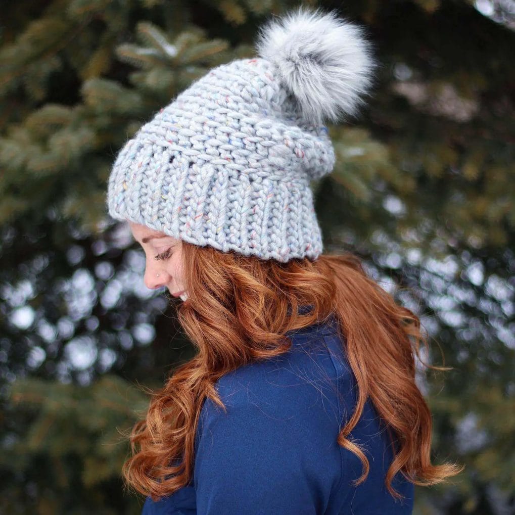 Soft auburn curls cascading under a cozy beanie for an elegant winter look.