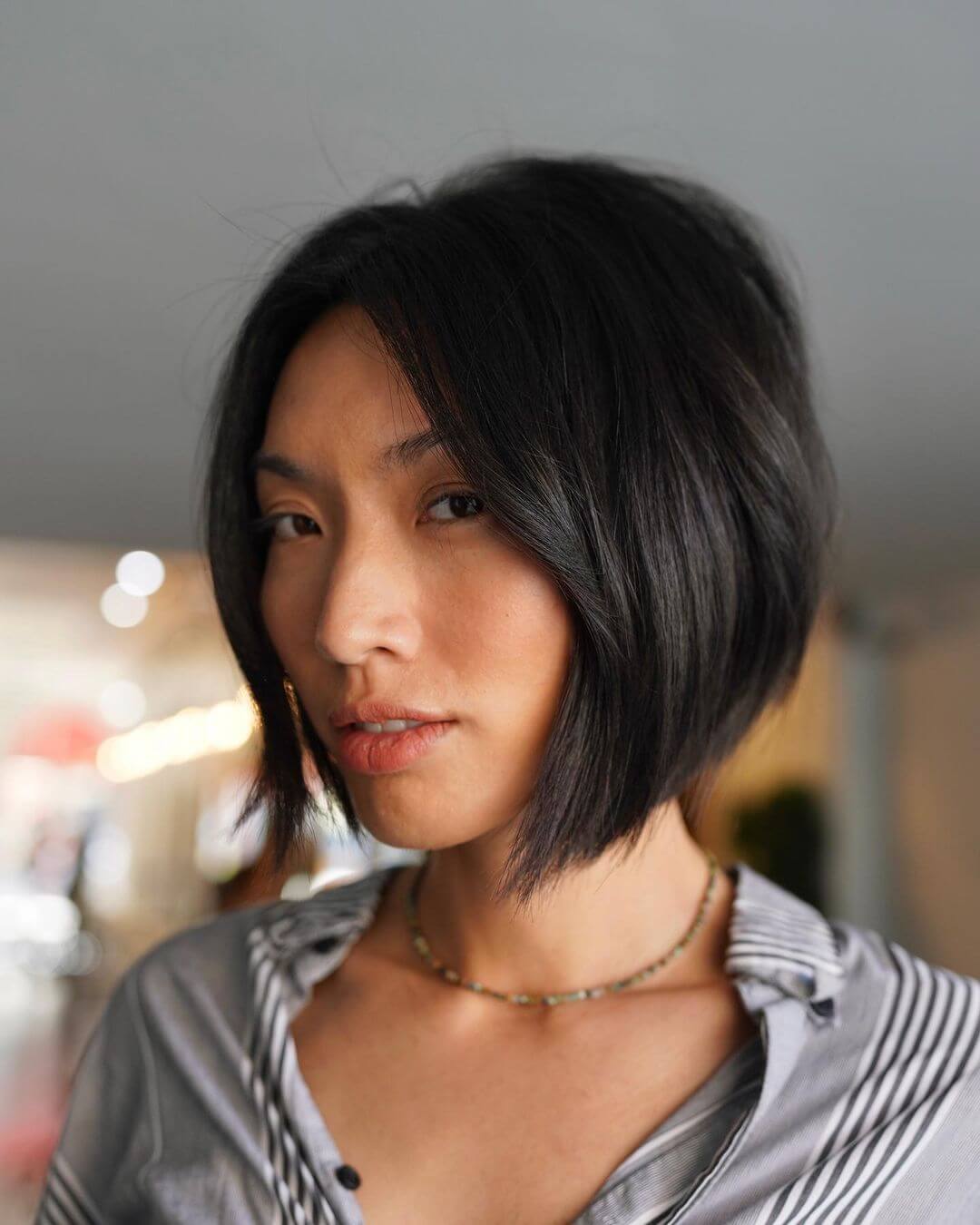 Soft blunt modern bob in deep black with a gentle side part.