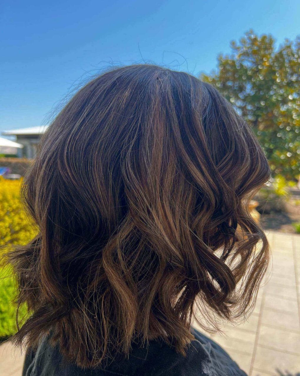 Soft bouncy waved bob with layered warm browns and honey highlights.