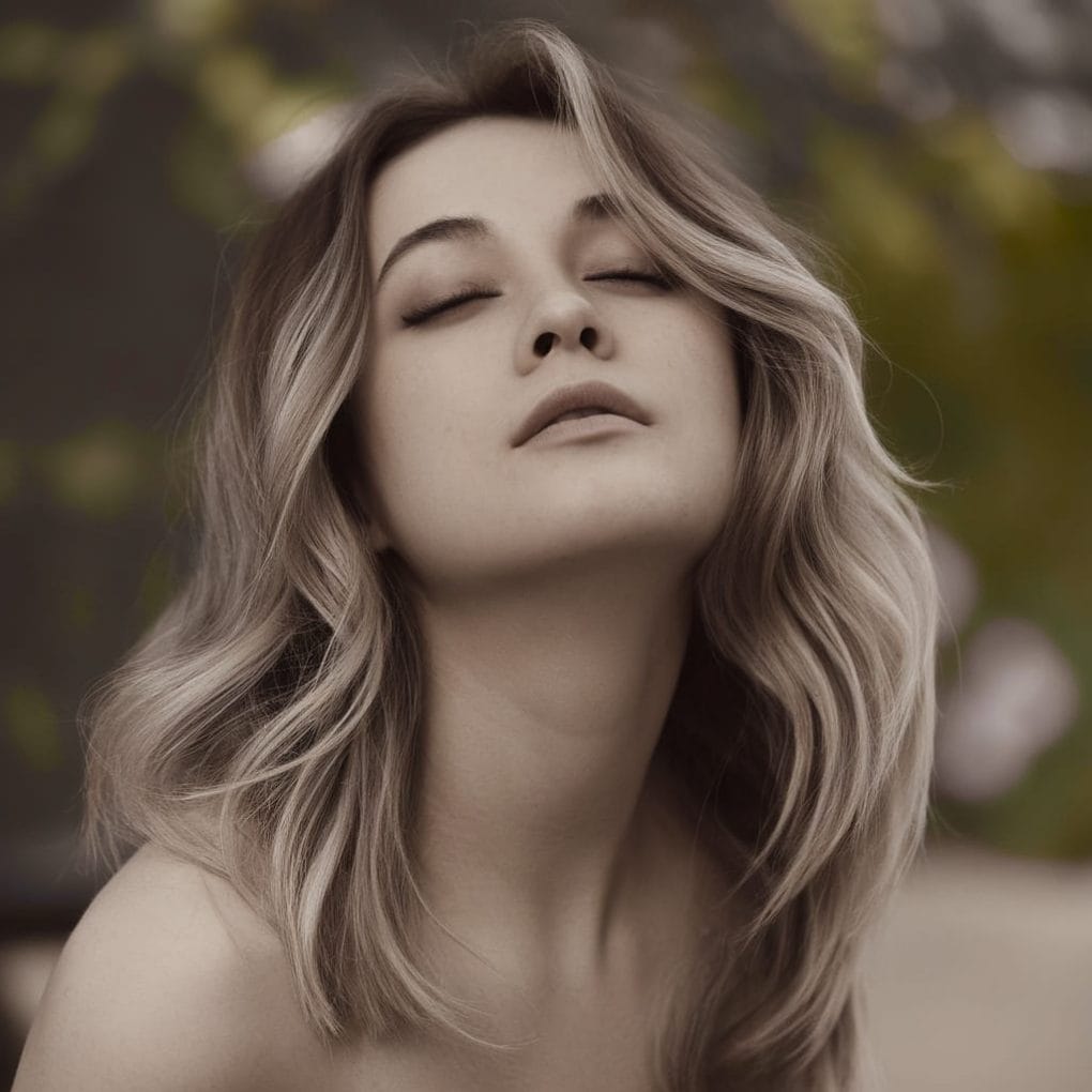 A young woman with soft, wavy hair, exuding a relaxed and romantic vibe.