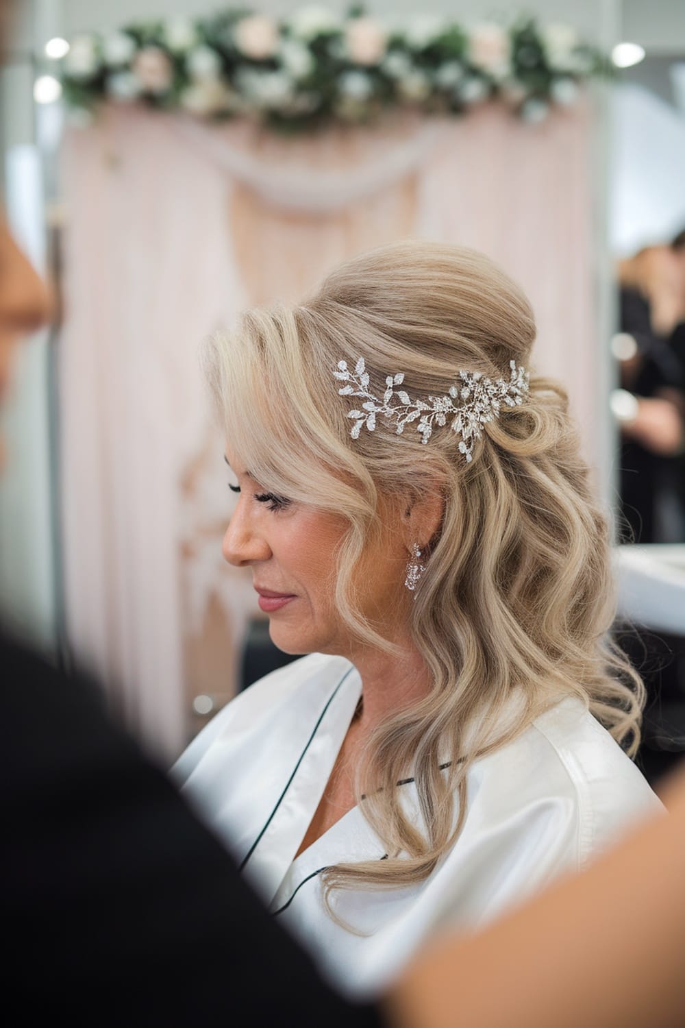 A woman with soft waves and a sparkling hairpiece, showcasing a beautiful hairstyle for the mother of the bride.