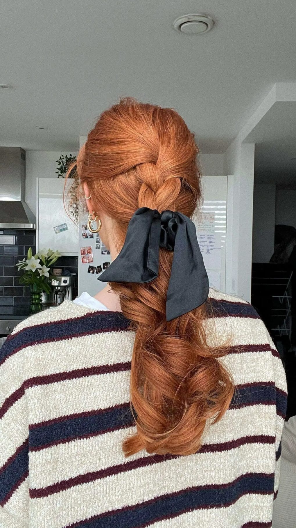 Sophisticated braided copper ponytail with a chic black bow for a birthday celebration.