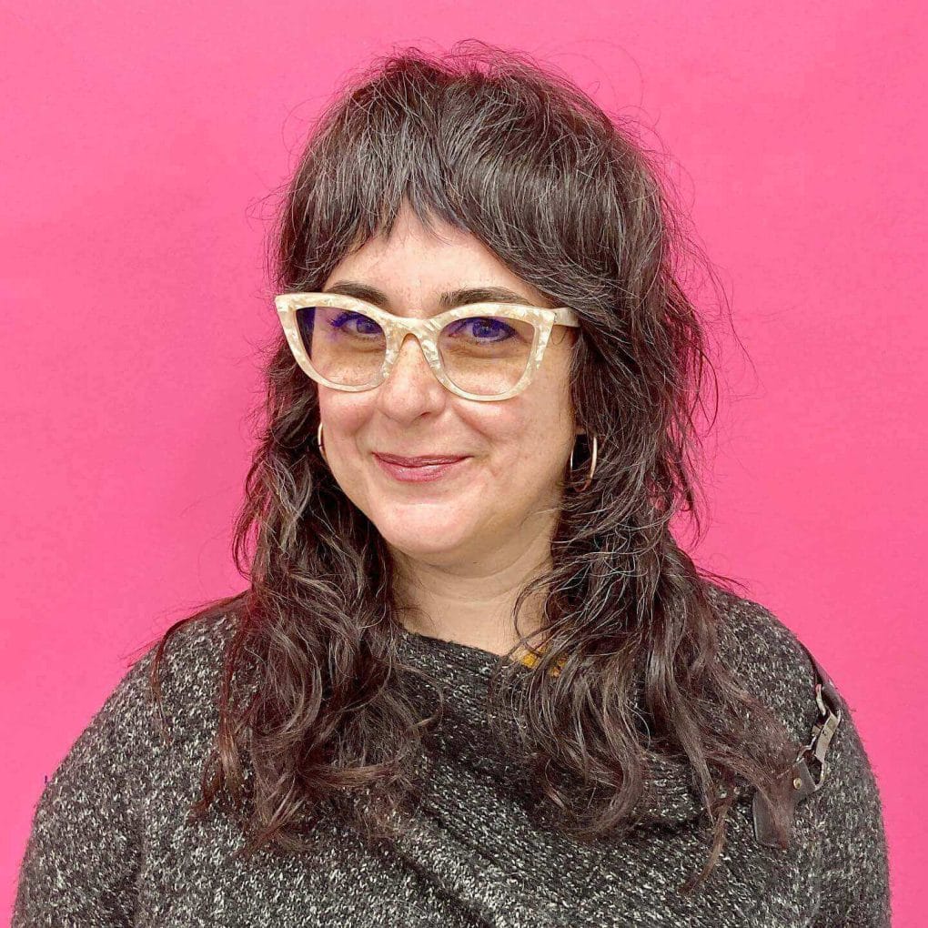 Medium-length wavy hair with playful curtain bangs.