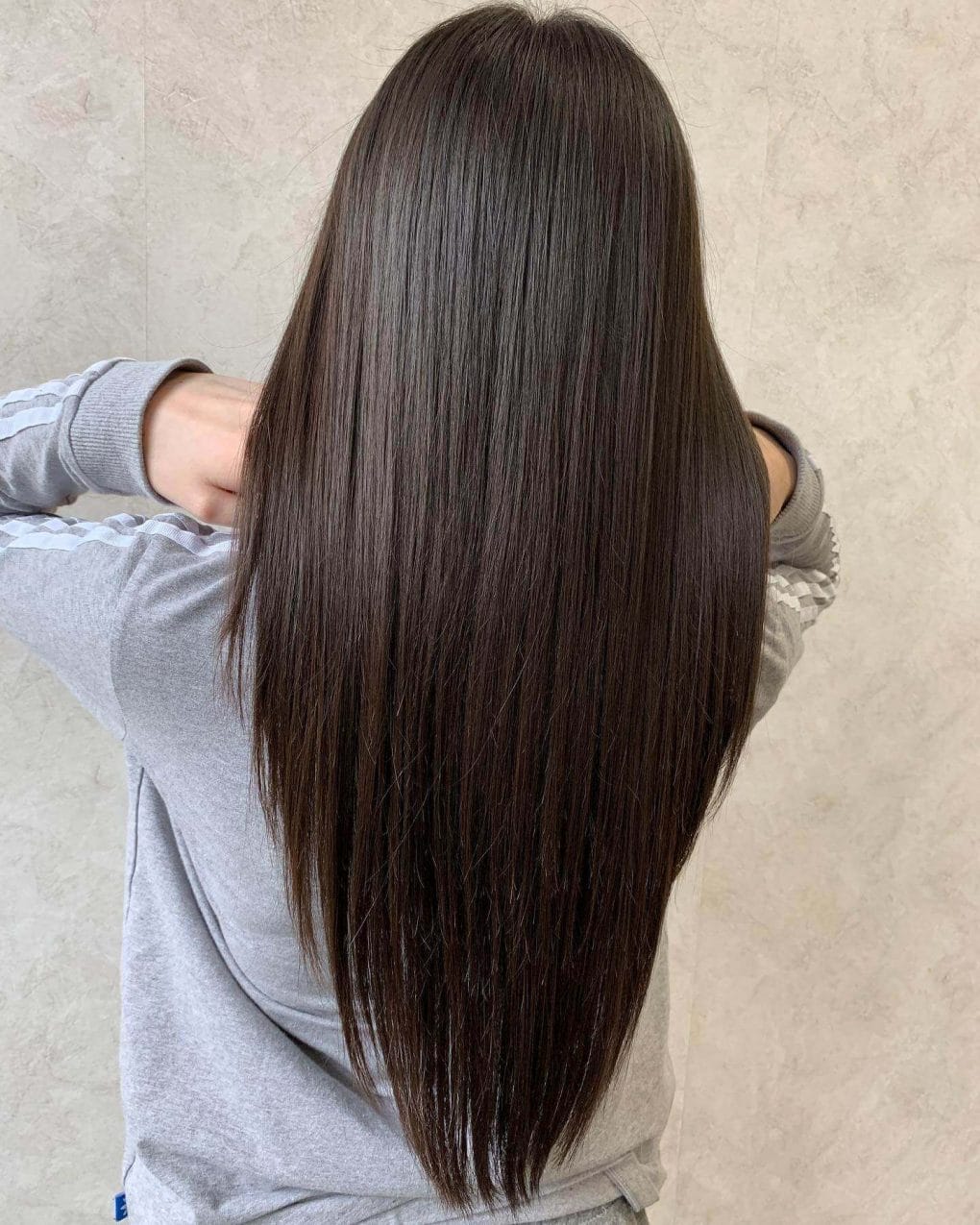 Long brunette hair styled in a V-layered cut for a sophisticated look.